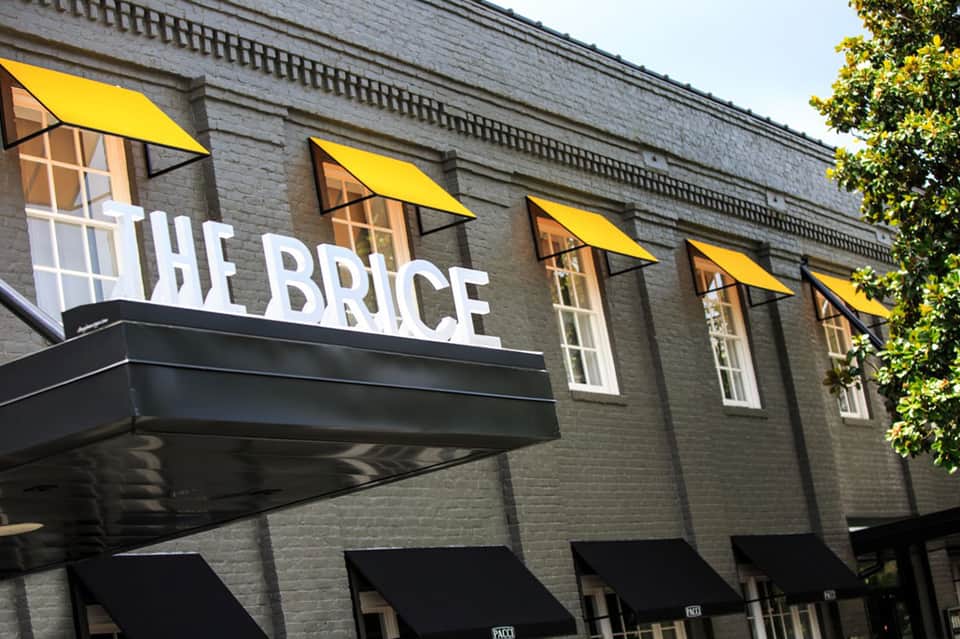 The Brice restaurant storefront with yellow awnings on brick building