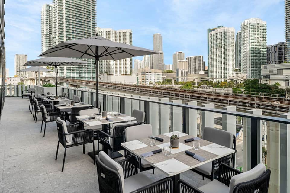 Rooftop dining terrace with city skyline views, umbrellas, and contemporary furniture