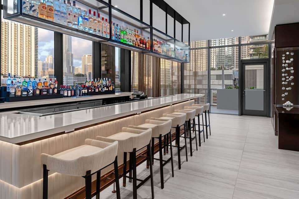 Upscale rooftop bar with city skyline views, white leather seating, and premium liquor display