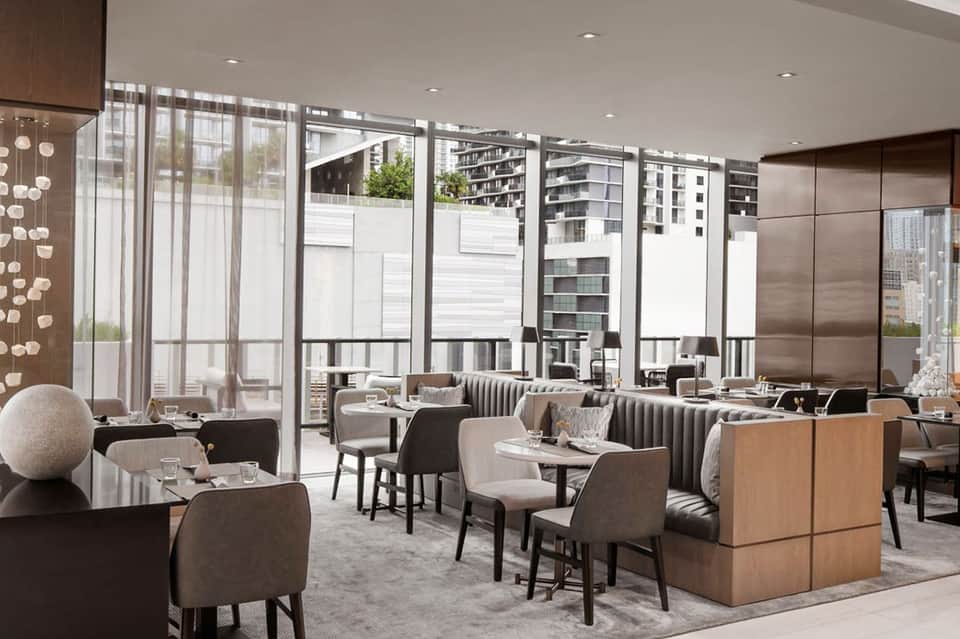Modern restaurant interior with contemporary seating, floor-to-ceiling windows, and city views