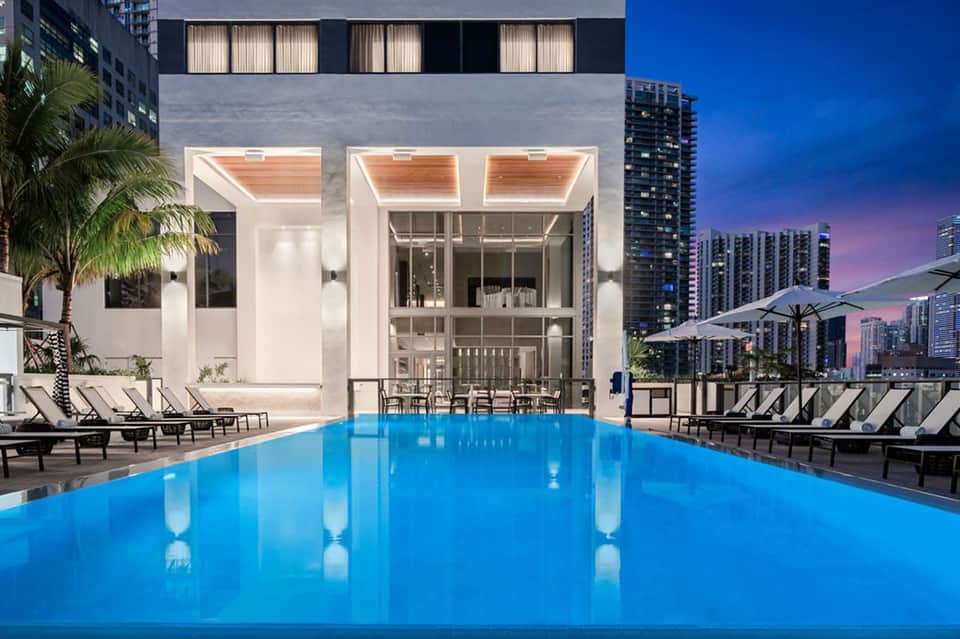 Modern rooftop pool with city skyline at dusk and lounge seating