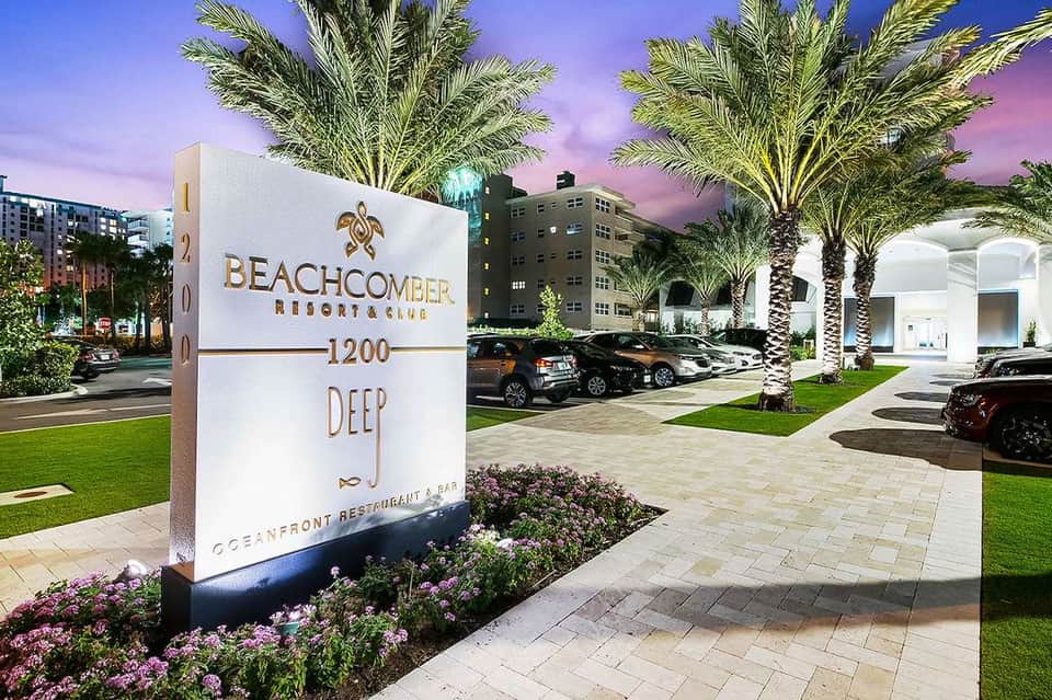 Beachcomber Resort signage with palm trees, modern entrance, parking area, and evening purple sky backdrop