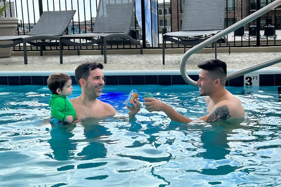 Father and child swimming in indoor pool with lounge chairs in background