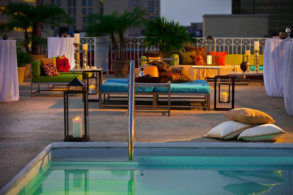 Upscale rooftop pool party setup with colorful cushions and city skyline.