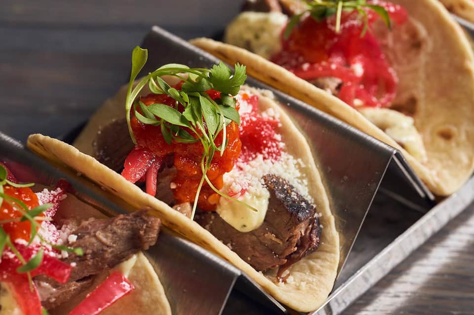 Gourmet chocolate tacos with strawberry garnish and red salt on dark serving plate