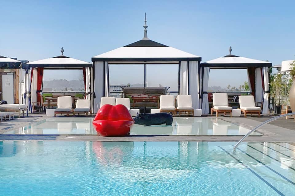 Luxury resort pool with black and white cabanas and red inflatable sculpture