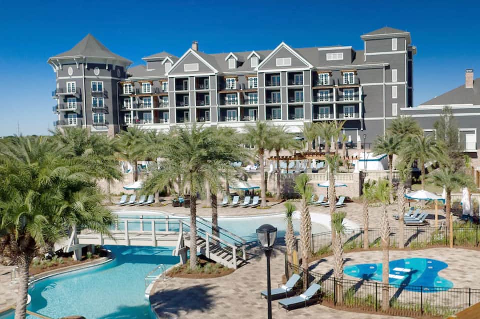 Beachfront resort with gray architecture, multiple pools, palm trees, and ocean access