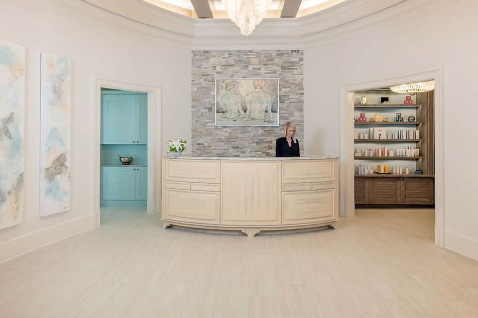 Elegant hotel lobby with curved reception desk, turquoise doors, marble accents, and built-in shelving