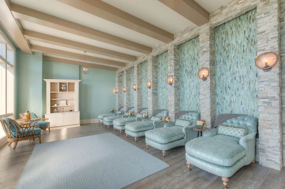 Spa relaxation room with mint-green accent walls, light blue loungers, fireplace, and pendant lighting