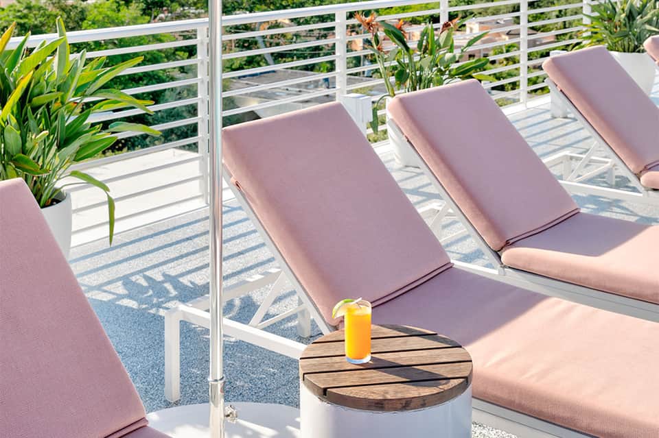 Oceanview deck with pink lounge chairs, white railings, and tropical plants
