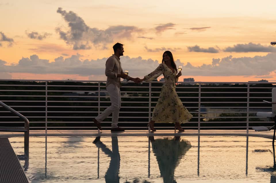 Couple dancing on a rooftop terrace during sunset with city skyline in the background