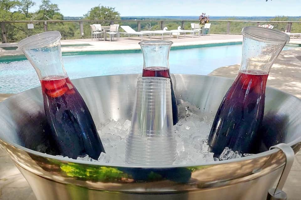 Three tropical cocktails with ice on table overlooking resort pool and landscape