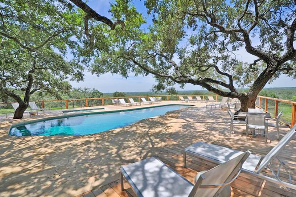 Resort pool surrounded by mature oak trees with lounge chairs and countryside views