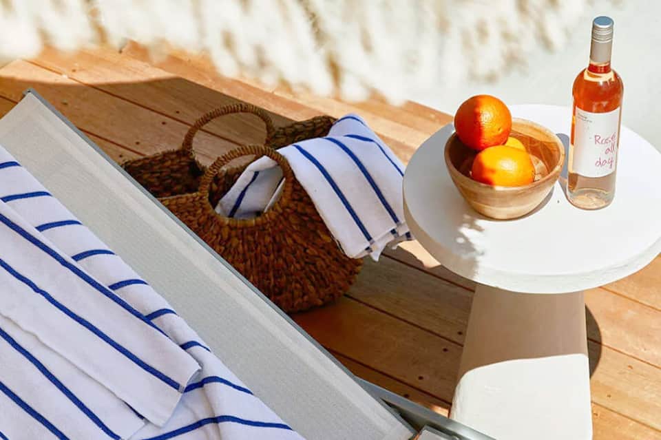 Beachside table with striped towel, basket, rosé wine, and fresh fruit