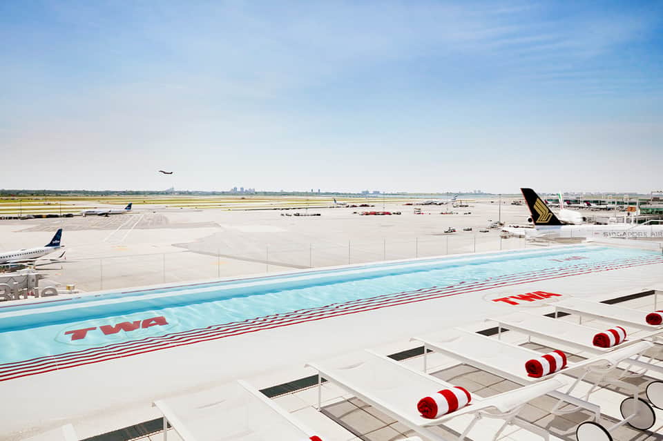 Aircraft wing and tail at airport with runway and aircraft in background during daylight
