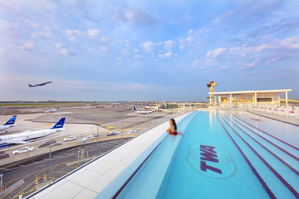 Woman in pool with airport runway view, commercial aircraft, and modern pool facility