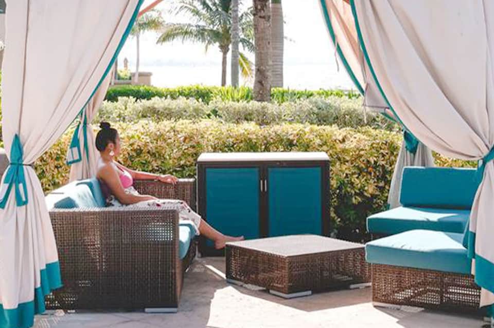Oceanfront cabana with flowing curtains, wicker furniture, and turquoise accents