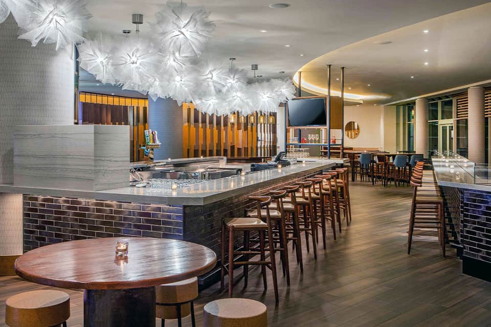 Modern resort bar and lounge with decorative white pendant lights and wooden accents