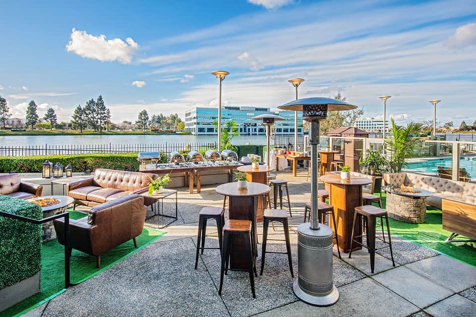 Upscale outdoor terrace with leather seating, firepit, and waterfront views