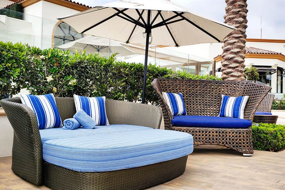 Outdoor lounge seating area with striped cushions, umbrellas, and palm trees at resort