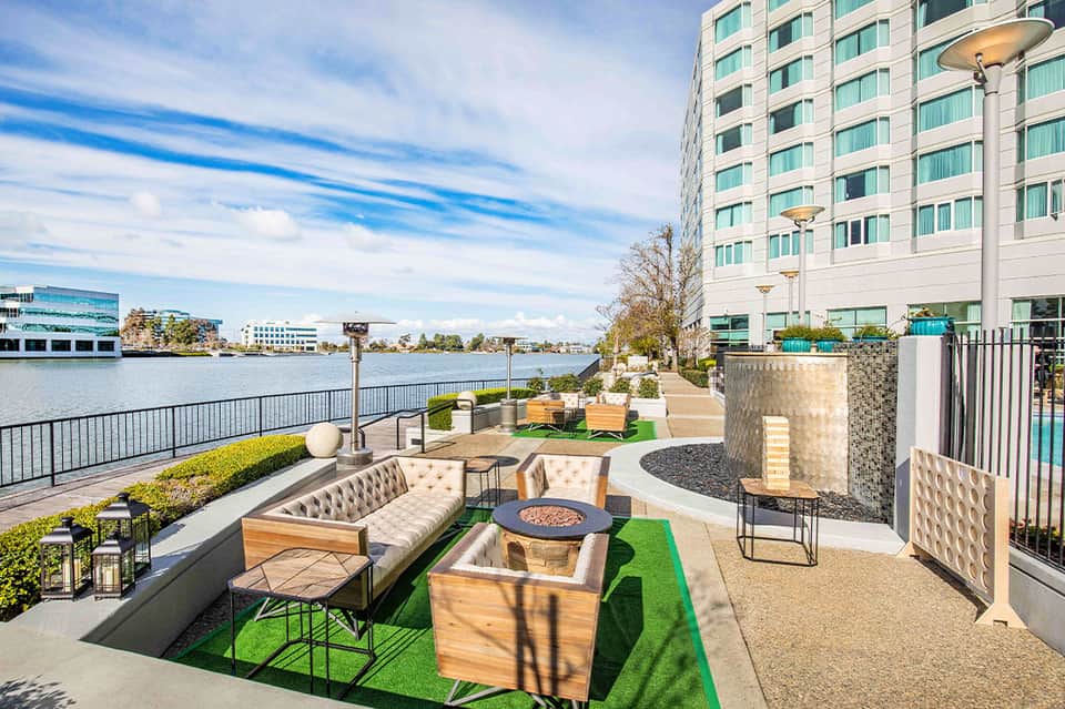Waterfront lounge area with fire pit, contemporary seating, and river views from tall building