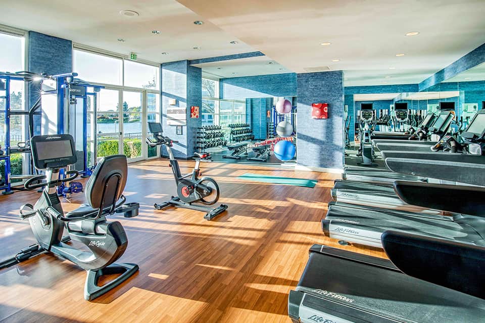 Bright fitness center with cardio equipment and water views