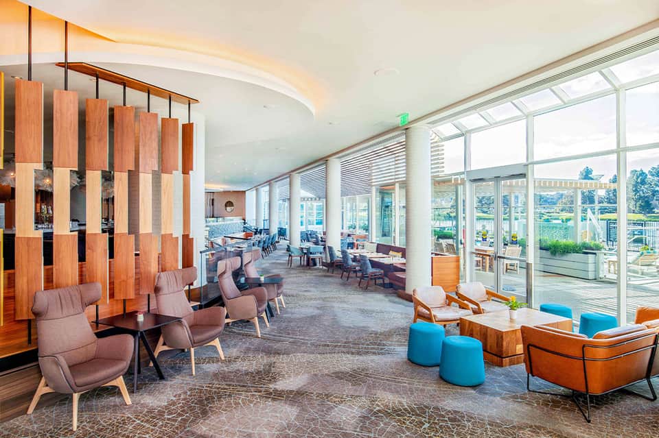 Modern hotel lounge with floor-to-ceiling windows, wooden design elements, and scenic outdoor view