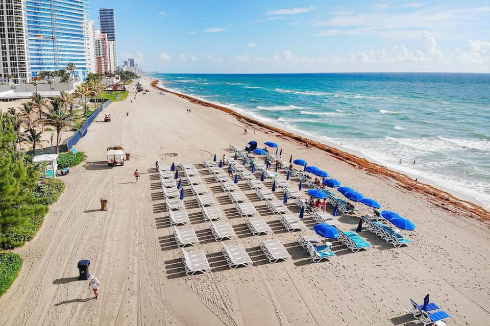 Aerial view of organized beach lounge chairs and umbrellas along sandy Florida coastline