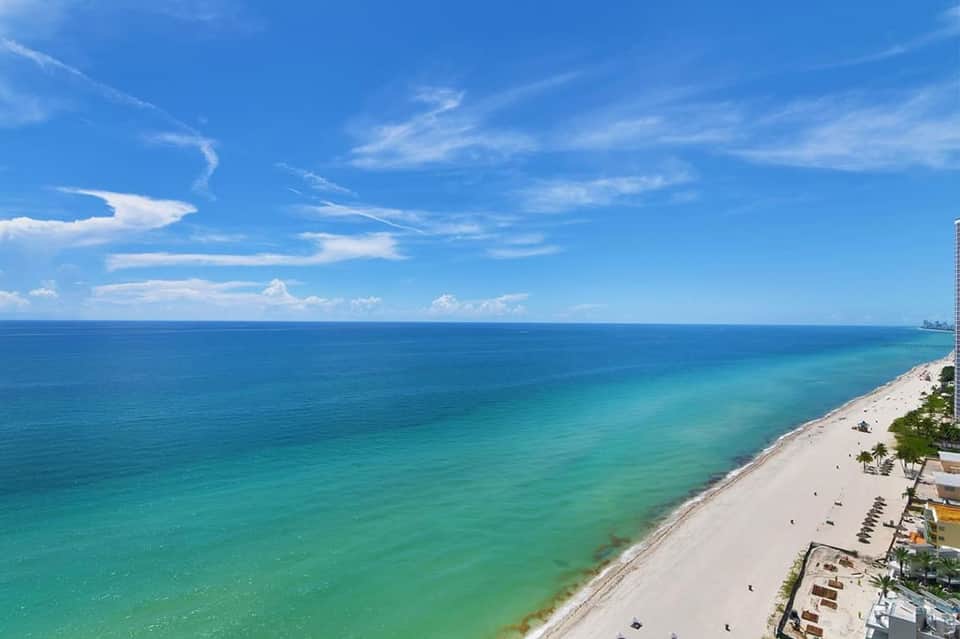 Pristine turquoise ocean and sandy beach stretching along a tropical coastal resort