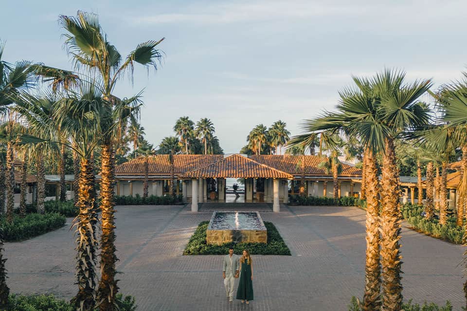 Beachfront resort courtyard with palm-lined grounds and Spanish colonial architecture