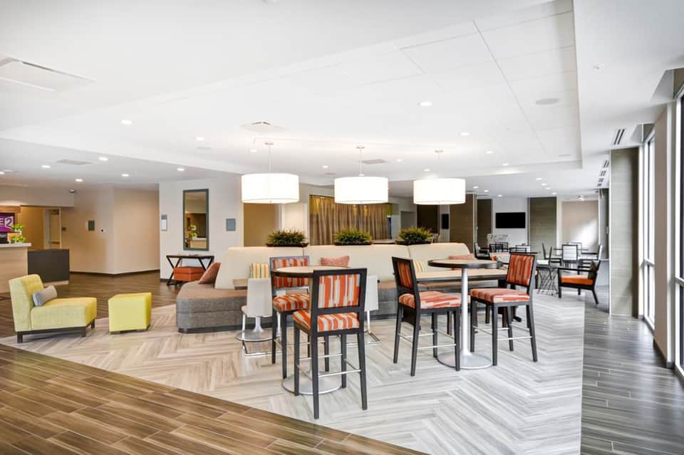 Contemporary hotel common area with lounge seating, dining tables, and reception desk