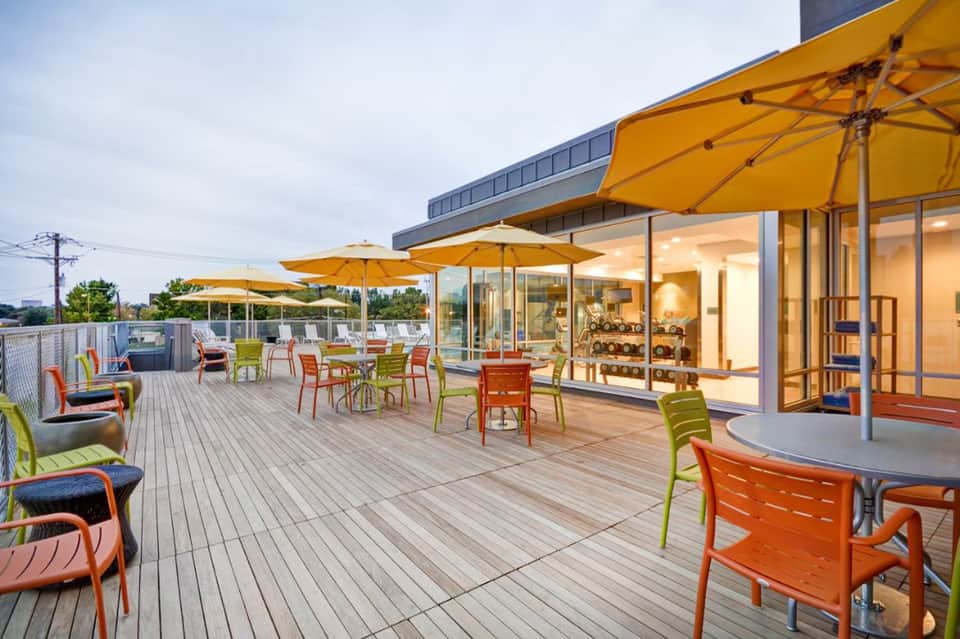Contemporary hotel terrace with yellow umbrellas, modern furniture, and glass building