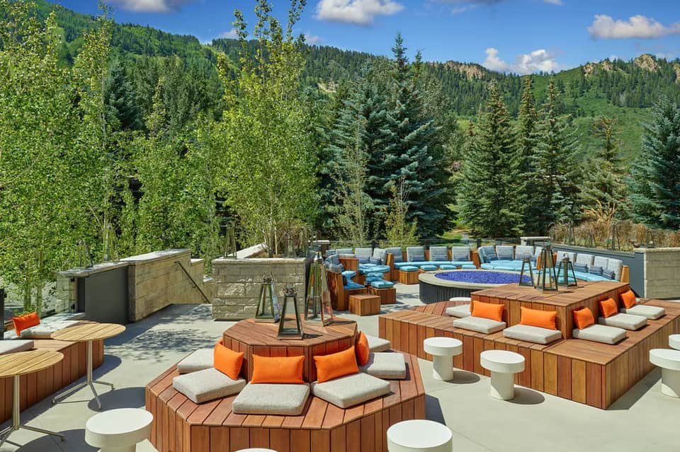 Mountain resort outdoor lounge with fire pits, wooden seating, and forest views