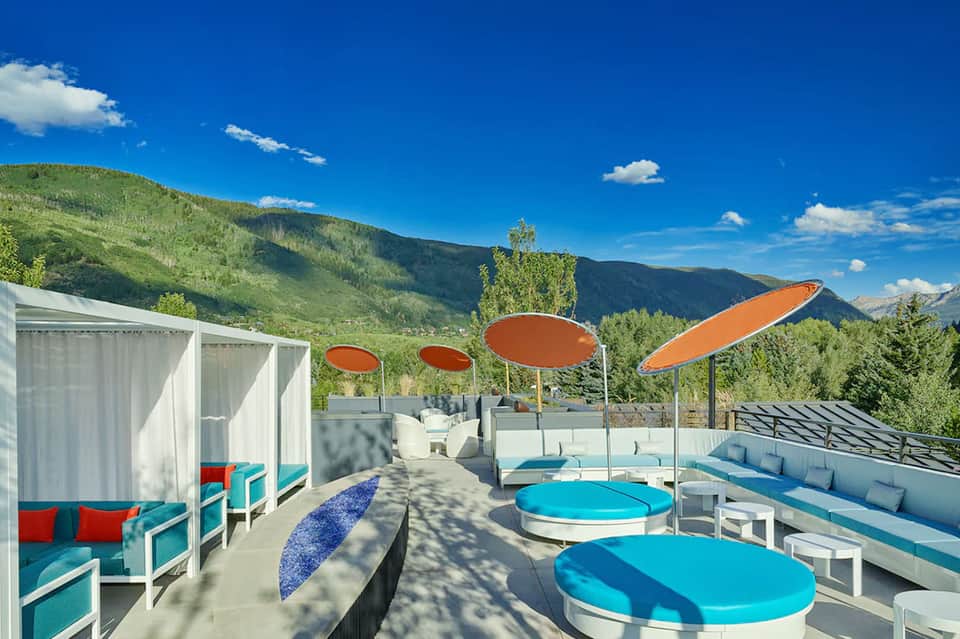 Rooftop lounge with colorful umbrellas, loungers, and mountain valley views