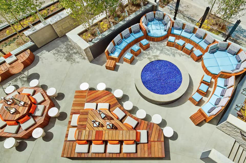 Aerial view of circular blue resort pool surrounded by wooden loungers and seating
