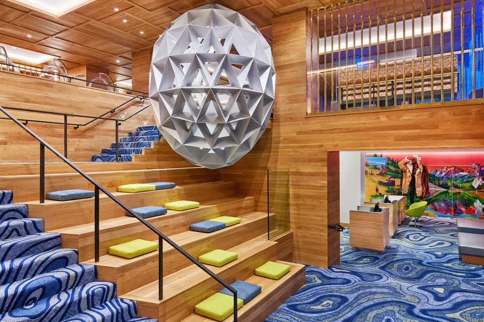 Modern interior staircase with geometric light fixture and colorful geometric floor pattern