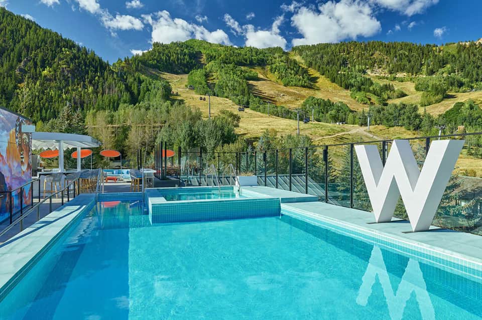 Modern pool facility with large W letter sign, mountain forest backdrop, and contemporary design