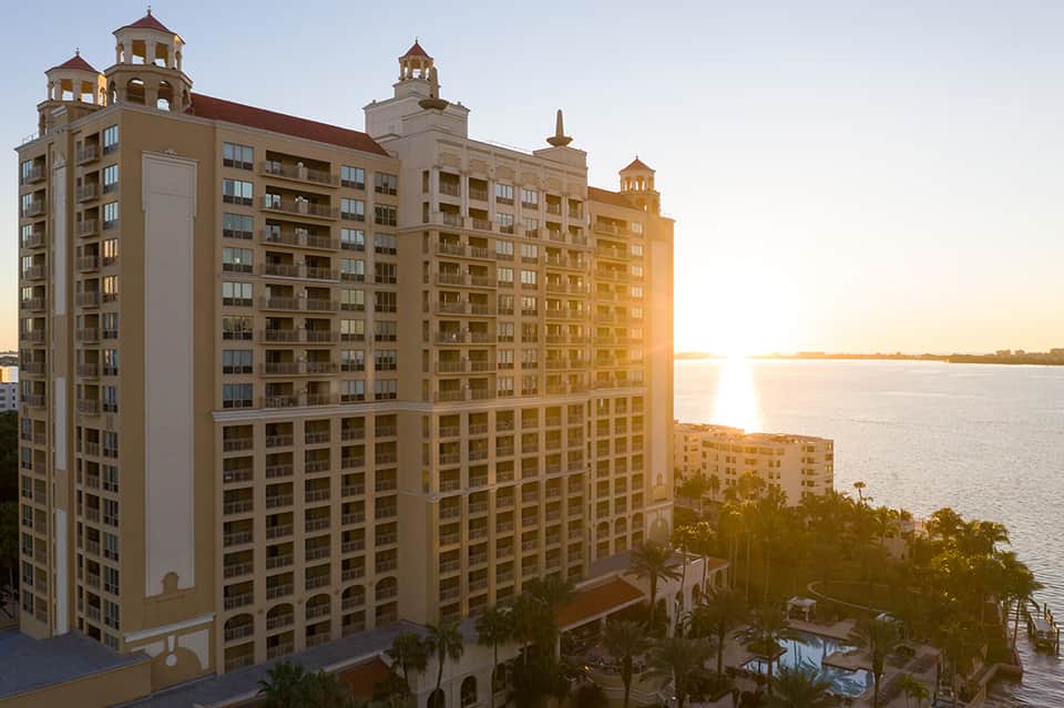 Luxury waterfront hotel tower at sunset with distinctive architecture and palm trees