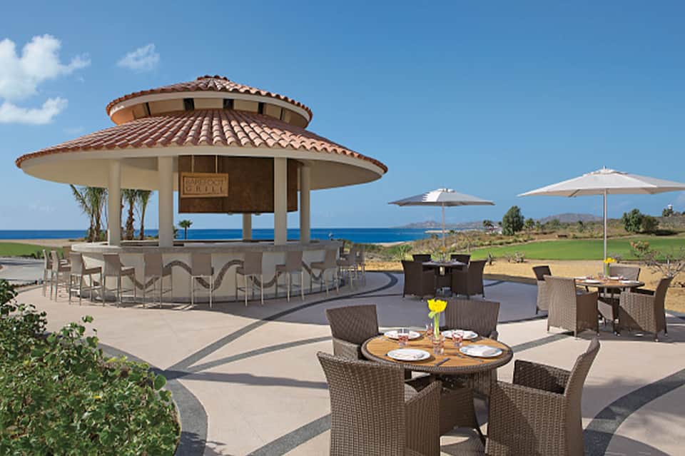 Beachfront grill pavilion with ocean views, dining tables, and tiki bar structure