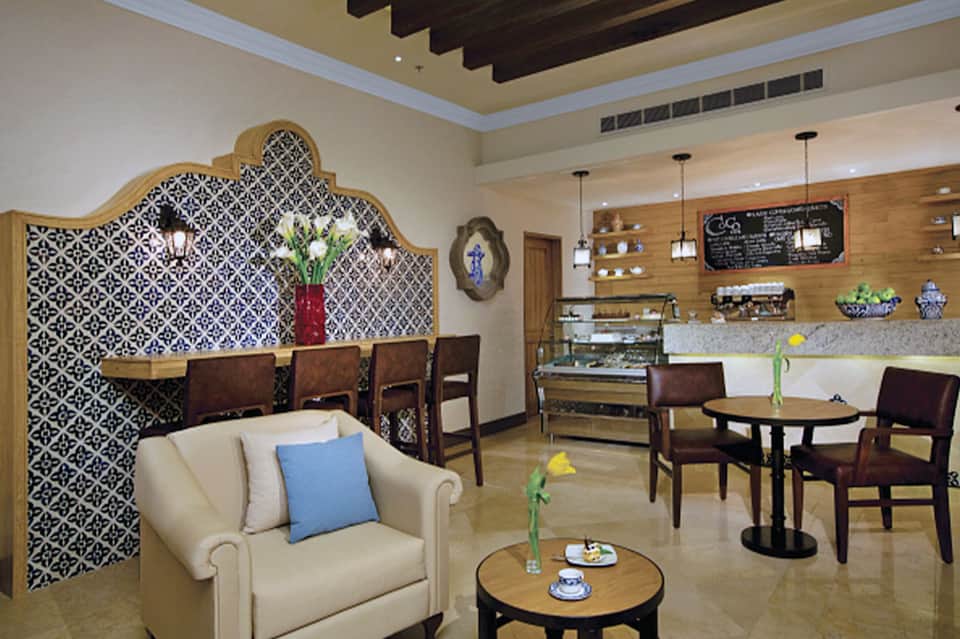 Modern hotel cafe with patterned gold screen, counter seating, and lounge area