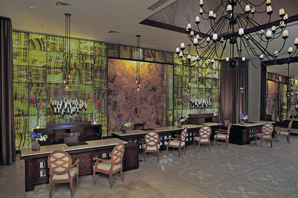 Luxury resort lobby with green lattice walls, elegant furnishings, and statement chandelier