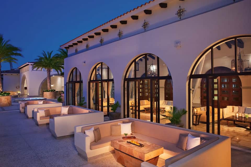 Upscale courtyard with arched windows, built-in seating, and ambient evening lighting