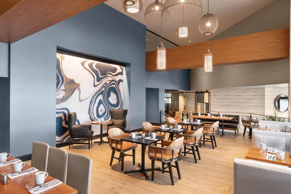 Modern restaurant dining room with blue accent wall, wooden beams, and pendant lighting