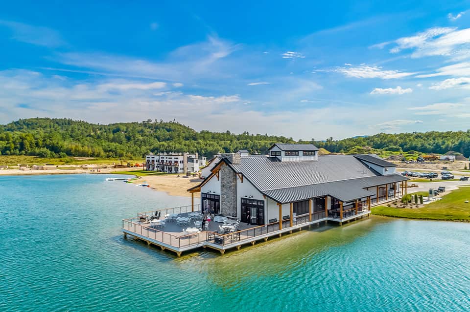 Modern waterfront lodge with dark roof, wooden accents, deck, and turquoise lake views