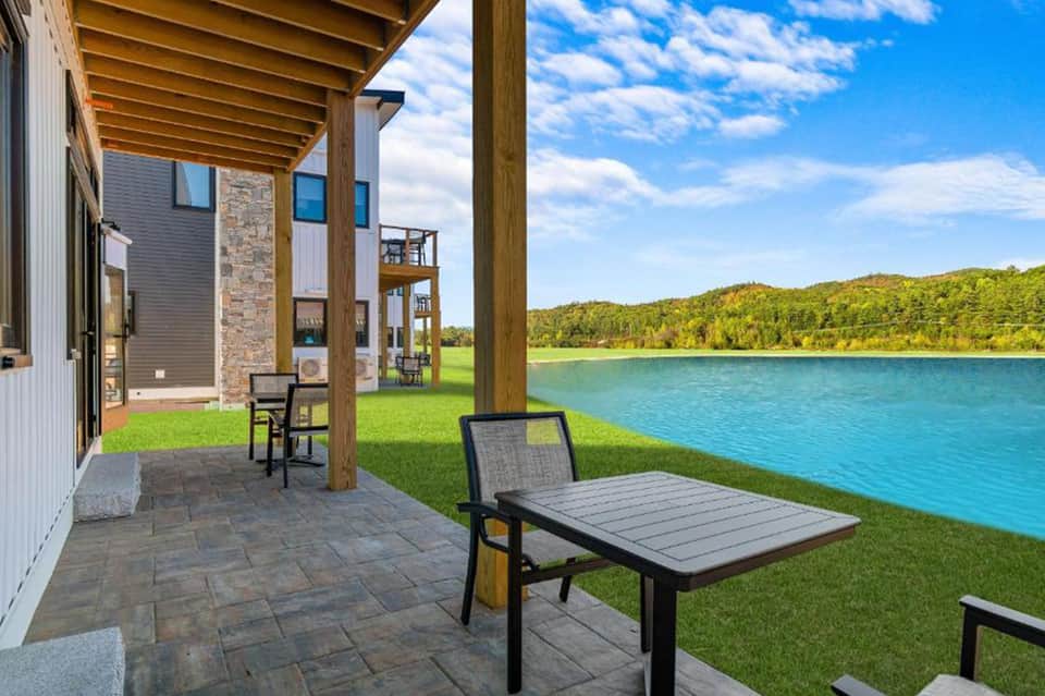Modern home patio overlooking scenic lake with pergola, green lawn, and mountains