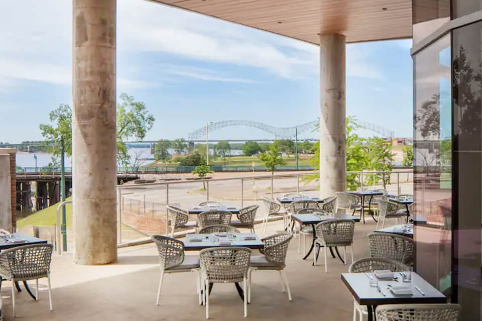 Waterfront restaurant patio with river bridge view and modern furnishings