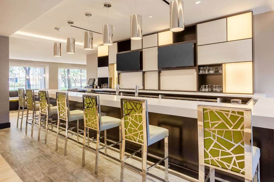 Modern hotel bar with lime green patterned chairs and contemporary light fixtures