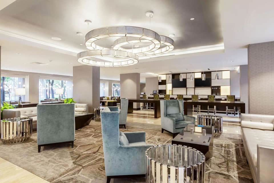 Elegant hotel lobby lounge with modern circular ceiling light, seating areas, and geometric accents