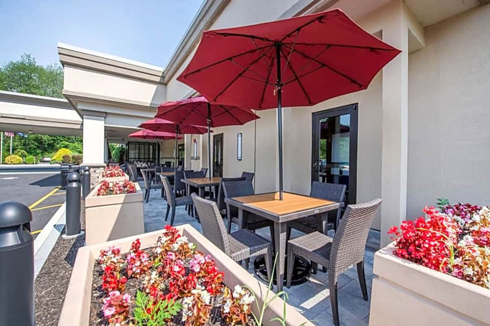 Outdoor patio with red umbrellas, dining tables, and flowering planters