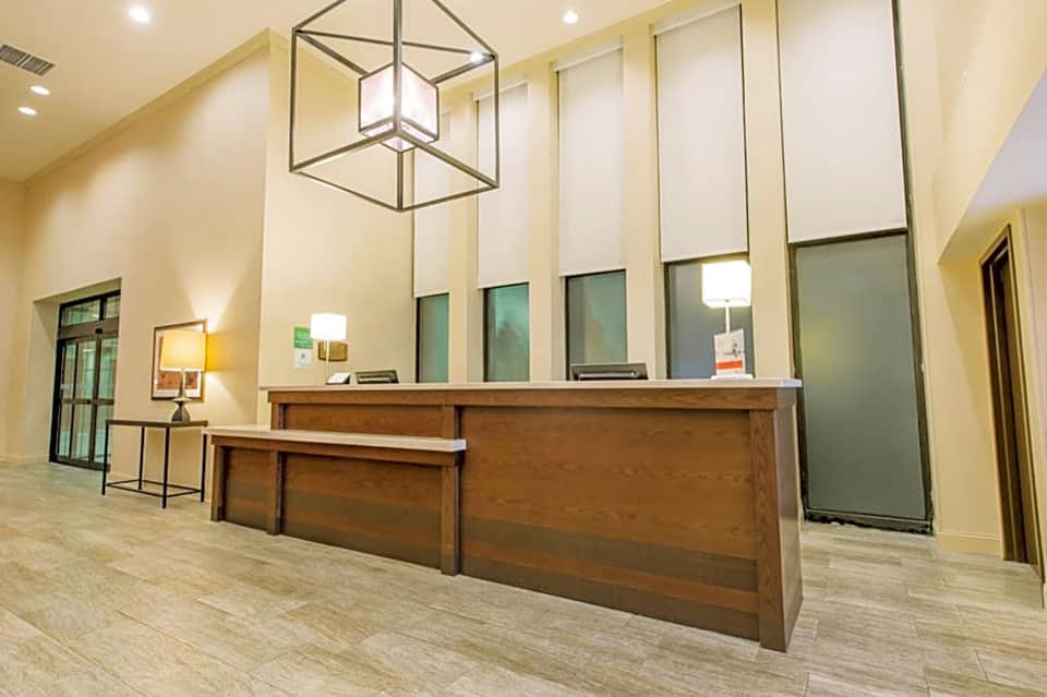 Hotel lobby with wooden reception desk, warm lighting, and modern architectural design